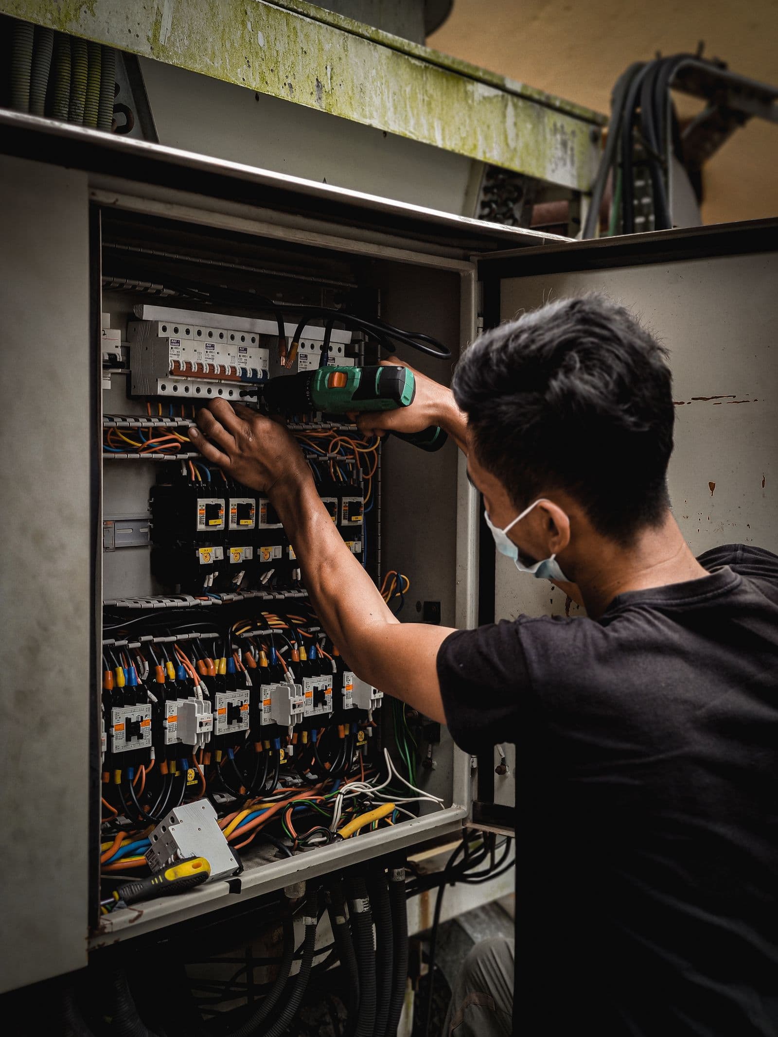Technician working on a circuit breaker panel indoors